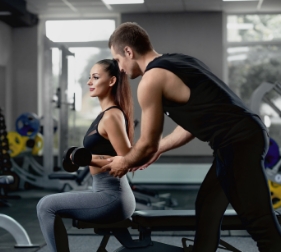 handsome-personal-instructor-helping-his-female-client-training-with-dumbbells