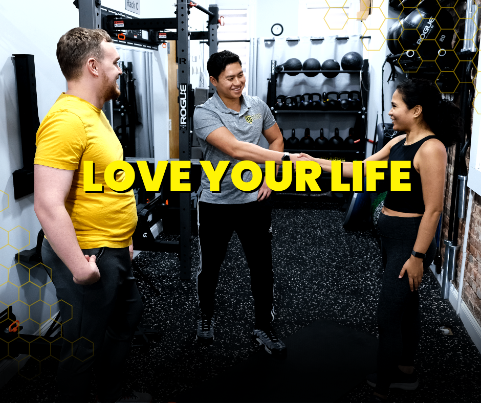 Two men and a woman engage in a discussion about a workout routine at The Hive Gym, a fitness studio in Jersey City. They are exchanging ideas and expertise, fostering a collaborative environment for fitness planning and goal-setting. The text on the image says 